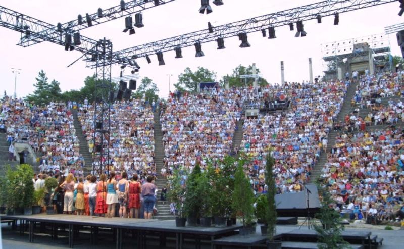 Théâtre romain rempli avec en 1er plan une chorale de dos sur scène